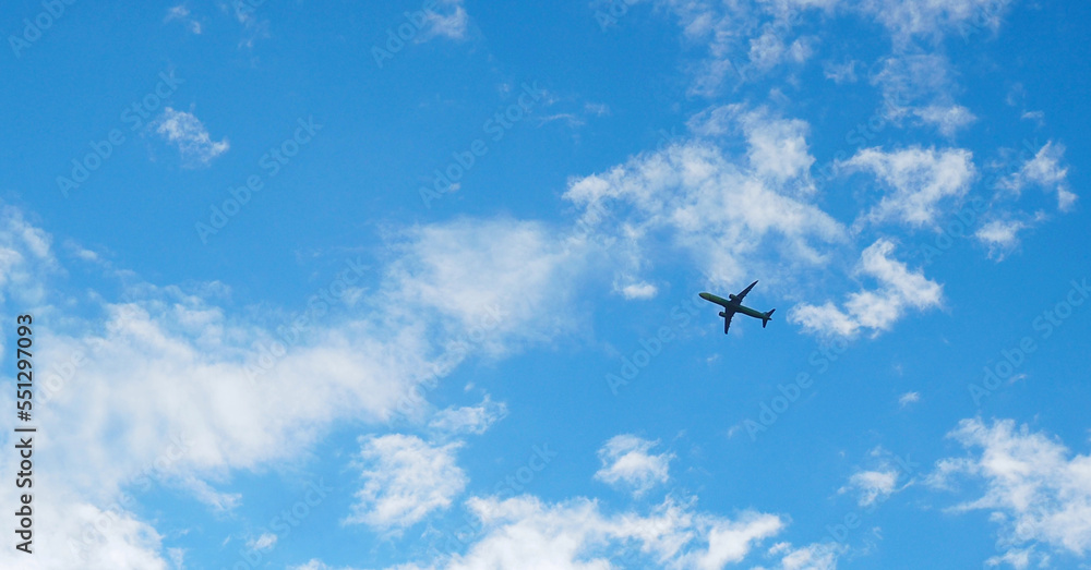 Wall mural the passenger airplane is flying far away in the blue sky and white clouds. aircraft in the air. int