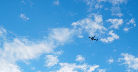 The passenger airplane is flying far away in the blue sky and white clouds. Aircraft in the air....