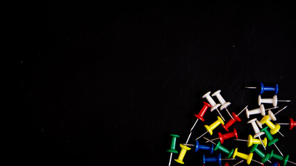 multicolored thumbtacks on a black background