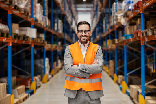 A successful small business owner is standing in warehouse and smiling at the camera.