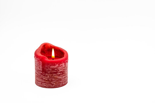 Eine rote brennende Kerze freigestellt vor wei&szlig;em Hintergrund als Weihnachtskarte oder Gru&szlig;karte f&uuml;r Advent