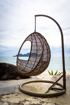 An Empty Egg Hammock Pod Chair On The Beach By The Sea