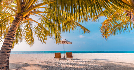 Beautiful panoramic nature. Tropical beach sunset as summer island landscape with chairs umbrella palm leaves calm sea shore, coast. Luxury travel panoramic destination banner for vacation or holiday
