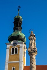 Low angle shot of a church and statue of saint against a blue sky in Koszeg, Hungary