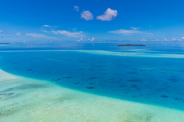 Fototapeta na wymiar Aerial panorama of the blue lagoon bay in Maldives islands. Blue sea surface from above shallow ocean view. Horizon with sunny blue sky. Idyllic travel aerial seascape skyline. Tranquil blue wallpaper