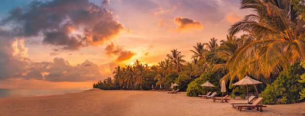 Fantastic panoramic view. Sandy shore with orange sunrise sunset sunlight over chairs palm trees....