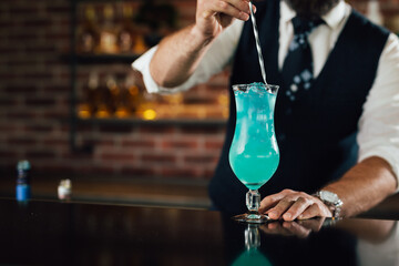 Bartenders hand mixes a blue cocktail