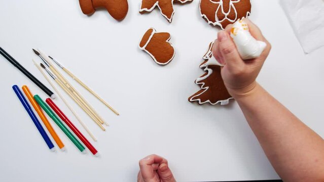 top view of a woman's hands decorating a Christmas gingerbread tree shape on the kitchen table