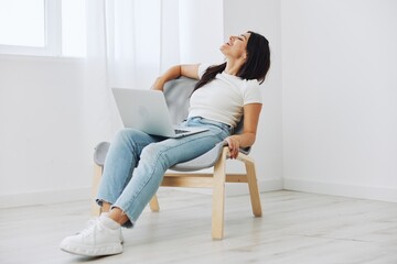 Woman relaxing at home sitting in a chair with a laptop, lifestyle home mood. Mockup, free copy space