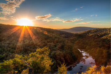 A sunset scene with sun rays beaming from a huge sun on Lee Bluff Lee Bluff looking over the St....