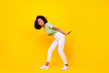 Fototapeta na wymiar Full body size photo of young adorable pretty cute nice woman hold hard rock look behind advert empty space isolated on yellow color background
