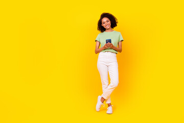 Fototapeta na wymiar Full length photo of young pretty cute nice attractive woman toothy beaming hold phone youtube vlog much likes popular isolated on yellow color background