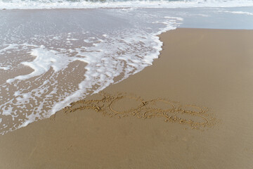Waves reaching the 2023 year sign on the beach at day time