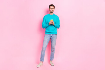 Full body photo of handsome young guy holding telephone email user subscribe wear trendy blue clothes isolated on pink color background