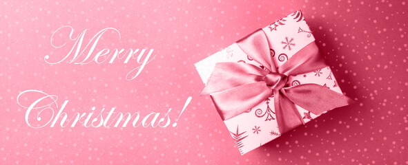 Fototapeta na wymiar Banner with gift box, caption Merry Christmas on backdrop with drawn snow in color 2023 Viva Magenta