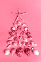 Seashells and starfish laid out as alternative Xmas tree. Trendy toning in color 2023 Viva Magenta.