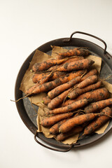 Fresh unwashed carrots in a metal tray