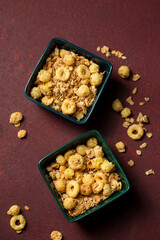 Dry breakfast granola in bowls on a burgundy background