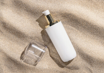 Blank one pump Cream bottle on beige sand close up, hard light. Cosmetic mockup