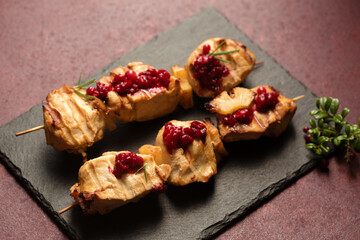 Chicken kebab with lingonberry sauce on a black stone tablet