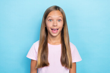 Fototapeta premium Portrait of cheerful impressed school girl with straight hairstyle wear pink t-shirt staring exited isolated on blue color background