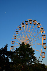 Fototapeta premium Switzerland, Geneva. Early morning moon and Ferris wheel. August 16, 2022.