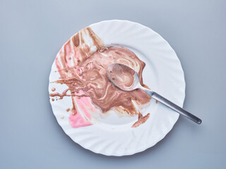 a white plate with a spoon and ice cream left overs