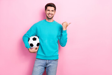 Photo of smiling satisfied good mood football player wear blue sweatshirt soccer ball finger direct...