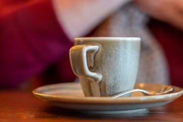 Close-up, a cup of coffee on a plate with a teaspoon, on a wooden table, a cozy and homely atmosphere