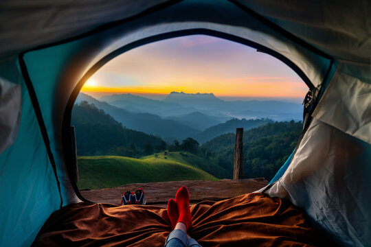 Woman cross leg on blanket in camping tent with sleeping bags on mountain hill. view from inside with Doi luang chiang dao mountains.