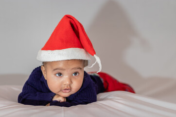 infant boy wearing Christmas red cap lying cute facial expression with white background at indoor