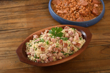 farofa with sausage, bacon and cabbage, typical Brazilian food, wood background	