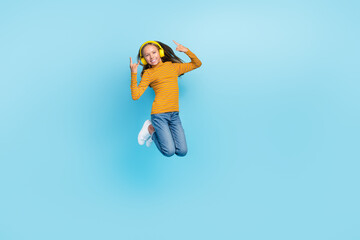 Full size photo of excited girl blond hair wear striped pullover jeans flying jumping listen new hits isolated on blue color background