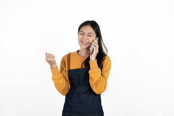 Happy young asian woman business owner wear apron and holding smartphone for checking order from...