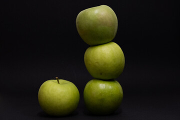 A Whole and a slice of apple on a black background, side view, Green apples, fresh, isolated on black, sliced apple on a stick