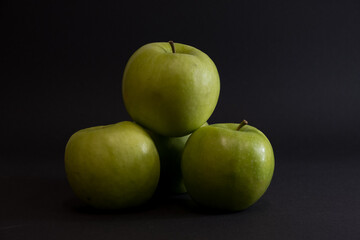 A Whole and a slice of apple on a black background, side view, Green apples, fresh, isolated on black, sliced apple on a stick