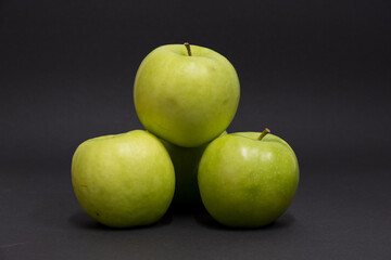 A Whole and a slice of apple on a black background, side view, Green apples, fresh, isolated on black, sliced apple on a stick