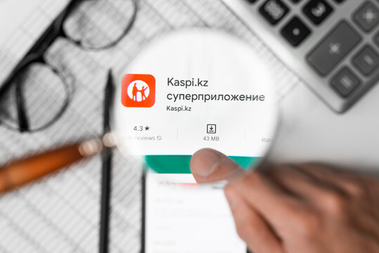 Kaspi Kz banking financial mobile application in online store on screen of smartphone at the workplace, view through magnifying glass. Astana, Kazakhstan 04.12.2022