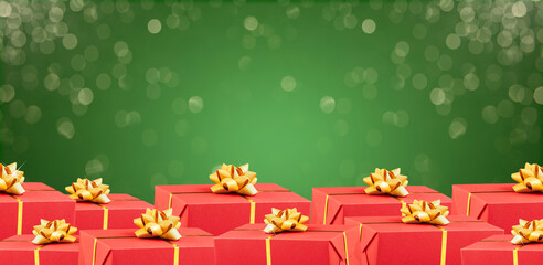 Christmas banner with many red gift boxes tied golden ribbons on green shiny XMas background. Happy...