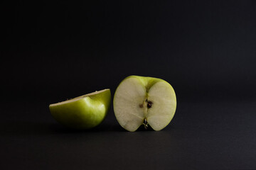 A Whole and a slice of apple on a black background, side view, Green apples, fresh, isolated on black, sliced apple on a stick