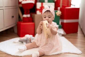 Adorable toddler playing tambourine sitting on floor by christmas gift at home - obrazy, fototapety, plakaty