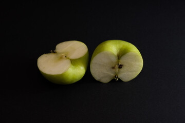 A Whole and a slice of apple on a black background, side view, Green apples, fresh, isolated on black, sliced apple on a stick