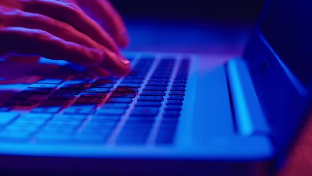Close-up of hands typing on a laptop keyboard.