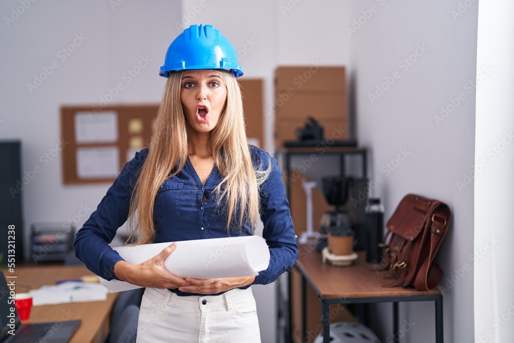 Sticker young woman wearing architect hardhat scared and amazed with open mouth for surprise, disbelief face