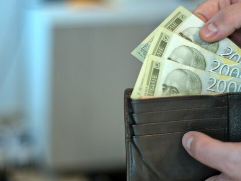 Close-up shot of 2000 Serbian dinar banknotes. A person takes money out of a wallet