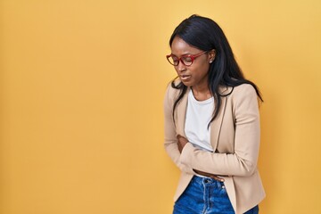 African young woman wearing glasses with hand on stomach because nausea, painful disease feeling unwell. ache concept.