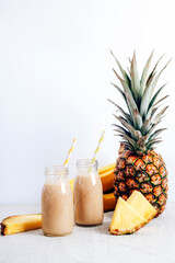 Pineapple smoothie in bottles with ingredients. Healthy raw vegan food. White background, copy space