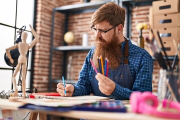 Young redhead man artist drawing on notebook at art studio
