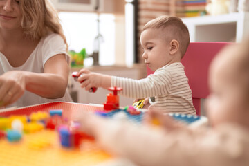 Obraz na płótnie Canvas Teacher and preschool student playing with car toy sitting on table at kindergarten