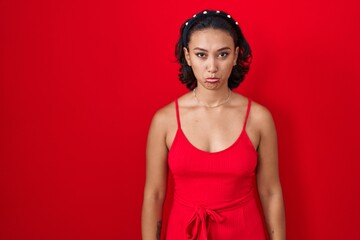 Young hispanic woman standing over red background depressed and worry for distress, crying angry...